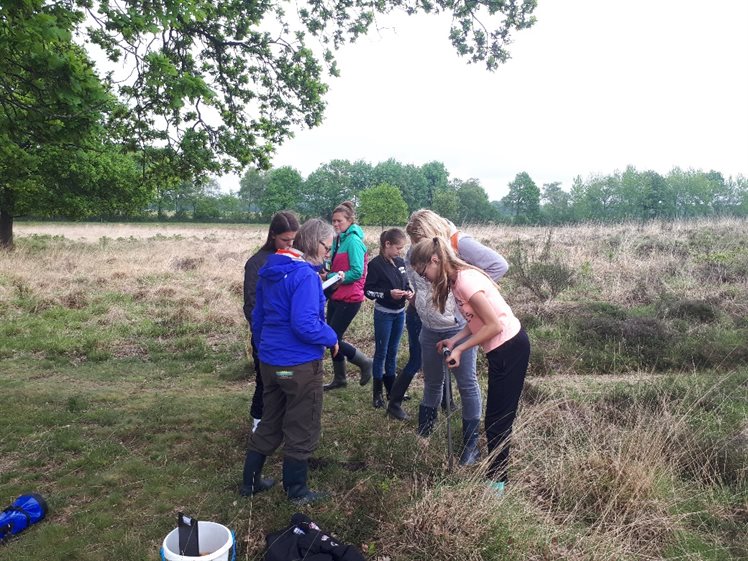 Anja Verbers, samen met een van de docenten en enkele leerlingen aan het boren in de mogelijke randwal (foto: Bart Koops).