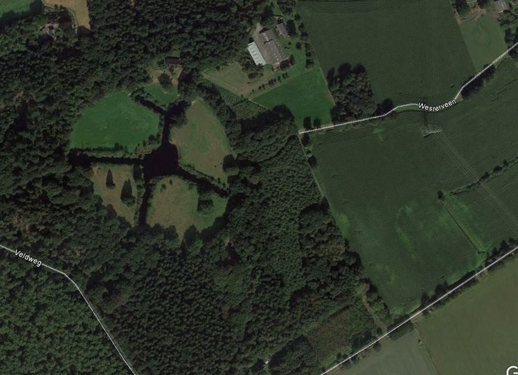 De luchtfoto van de onderzoek locatie in Norg (in blauwe cirkel). Het bos in deze laagte is herkenbaar anders dan in het gebied er omheen. Ook in de akker zie je een kleurverschil.