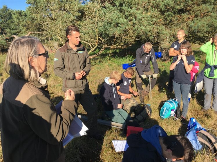 De Junior Rangers van het Dwingelderveld krijgen uitleg van Anja Verbers over hoe je het landschap kunt lezen, wat pingoruïnes zijn en hoe je ze kunt onderzoeken door middel van het boren. (foto: Gert Koene)